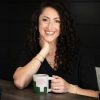 Laura Williams, PT, DPT, PWCS - CEO Hearth Healing and Founder of Deep Core Restore sitting at a wood table with a coffee mug
